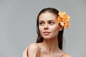 Canvas Print - Young woman with a flower in her hair, showcasing a serene expression and soft lighting against a minimalist background. Bright, fresh, and vibrant colors.