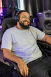 © Bogdan Pictures - A relaxed music producer, who is wearing stylish headphones and has a big smile on their face, is working in a modern home studio that is equipped with highquality professional audio equipment