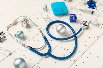 Wall Mural - Composition with stethoscope, medicines and Christmas decorations on light wooden background