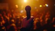 © vetrana - Engaging public speaking  a hand holding a microphone before a blurred audience at a live event