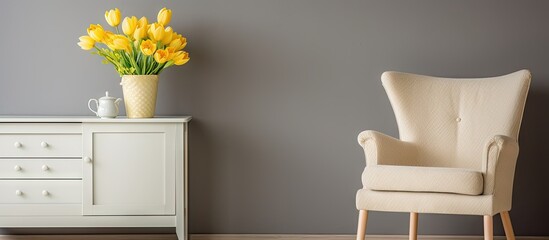 Fototapete - Vintage armchair in cream with light grey wall, elegant white cabinet beside yellow daffodils in pale jug, creating a cozy atmosphere.