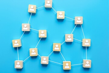 Poster - Wooden blocks with people icons linked by white lines on blue background. Concept of social networking, teamwork, communication, and connections.