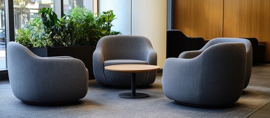 Aufkleber - Cozy modern seating area with three grey rounded armchairs surrounding a wooden coffee table on a textured floor near large windows and greenery.
