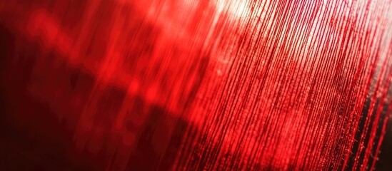 Poster - Vibrant red weaving thread with a smooth texture creating an abstract background; light reflections enhance the depth and visual interest.