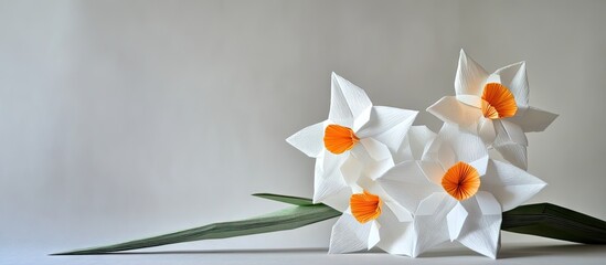 Poster - Delicate white origami narcissus flowers with vibrant orange centers arranged gracefully on a soft gray background with green leaves.