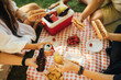 © polinaloves - Happy people having picnic with hot dogs and cold drinks, sitting on a plaid in a park.