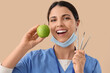 © Pixel-Shot - Female dentist with apple and tools on beige background, closeup