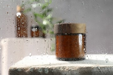 Canvas Print - Body care product in jar on stone surface, view through wet glass. Space for text