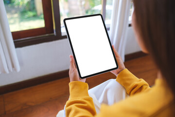 Wall Mural - Mockup image of a woman holding tablet with blank desktop white screen at home