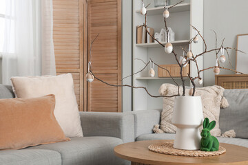 Wall Mural - Vase with tree branches and Easter eggs on coffee table in festive living room, closeup