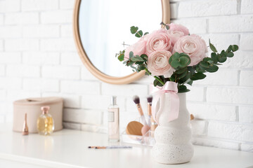 Canvas Print - Vase with bouquet of beautiful ranunculus flowers and cosmetics on dressing table near white brick wall, closeup