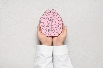 Poster - Female hands with paper human brain on light background. Cancer concept