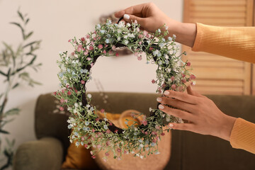 Canvas Print - Female hands with Easter wreath in living room, closeup