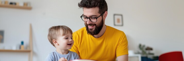 Wall Mural - A man and a boy are sitting at a table with a bowl of food in front of them. The man is smiling and the boy is laughing. Scene is happy and warm, as the father