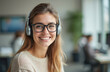 © Viktor - Smiling woman with glasses, headset looks at camera. Businesswoman works, studies online. Agent, consultant provides client assistance. Modern office interior at background. Portrait of pro service