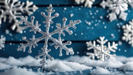 Aufkleber - Silver snowflakes nestled in artificial snow on a blue wooden background showcasing enchanting Christmas decor for holiday celebrations.