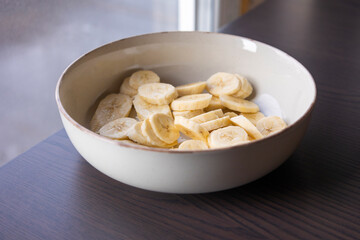 Wall Mural - fresh banana slices in a white bowl close-up