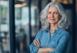© Enigma - Portrait of a confident, mature businesswoman standing in a modern office, arms crossed and radiating professionalism, strength, and leadership in her successful career