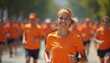 © Viktor - Smiling woman runs in orange shirt with crowd at charity event. Female runner participates in marathon race. Healthy lifestyle, sport activity, fun, community support, health awareness promotion.