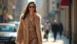 © Viktor - Fashionable woman walks in city wearing chic fur coat, sunglasses. Glamour model posing on street. Girl with long brown hair, elegant dress, confident look. Urban lifestyle. Street style. Sunny day.