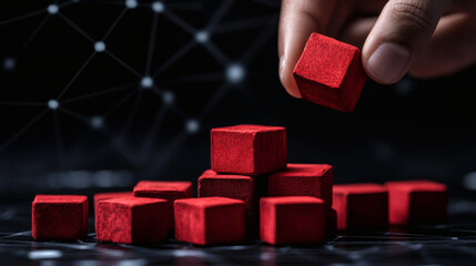 Aufkleber - Red blocks being arranged by a hand against a dark background