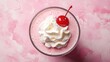 © Matcha_09 - A top-down view of a glass of strawberry milkshake topped with whipped cream and a cherry.