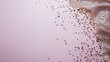 © lililia - Golden confetti is artistically arranged on a soft pink background, setting a joyful mood for special occasions or celebrations