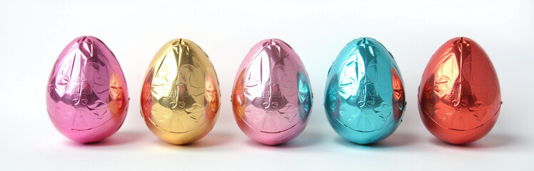 Aufkleber - Chocolate Eggs Wrapped In Bright Foil Are Set Against A Clean White Background As Part Of A Colorful Banner Design.