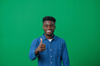 © apimagine - A smiling young man in a blue shirt is giving a thumbs up against a green background.