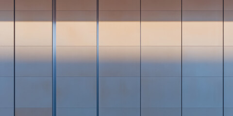 Wall Mural - Sunlight casting shadows on a modern building facade during late afternoon