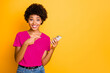 © deagreez - Copyspace photo of stylish trendy cheerful cute pretty charming girlfriend pointing at her phone held with her hands wearing jeans denim t-shirt while isolated with yellow vivid color background