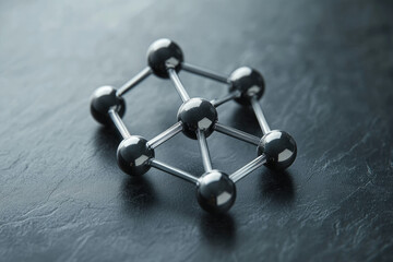 Aufkleber - A metallic molecular model rests on a dark surface, showcasing interconnected spheres and rods, representing atomic bonds and structures.