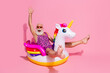 © deagreez - Elderly man in leopard print bodysuit enjoying a fun moment on unicorn float against vibrant pink background