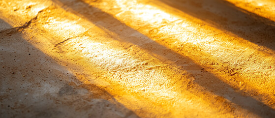 Poster - Golden hour light casting long shadows on textured sand background, creating warm and serene atmosphere