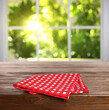 © New Africa - Red checkered tablecloth on wooden table in room against blurred sunlit window, closeup