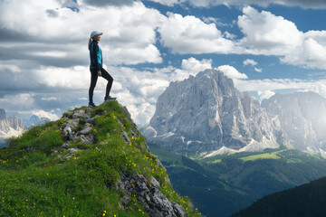 Wall Mural - girl on the mountain peak with yellow flowers and green grass in beautiful alpine mountain valley at