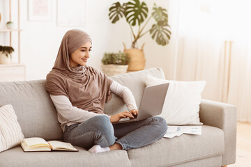 Poster - Remote Business. Happy Arabic Businesswoman Working With Laptop And Documents At Home, Sitting On Comfortable Couch At Home