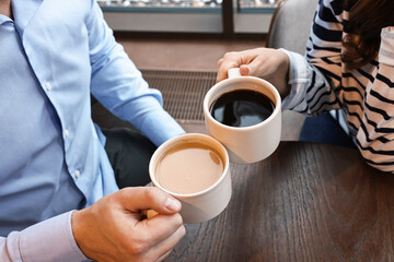 Wall Mural - Colleagues having coffee break at wooden table in cafe, closeup