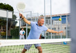 © JackF - Portrait of sporty senior man playing padel on open court on autumn day, ready to hit ball. Health and active lifestyle concept..