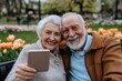 © Milos - An elderly couple joyfully takes a selfie surrounded by blooming tulips, representing the enduring love and happiness that flourishes even in later years of life.