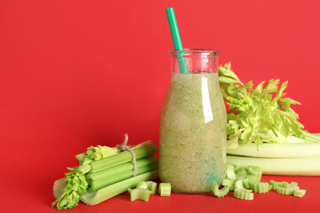 Wall Mural - Bottle of celery juice with chopped and whole celery on red background