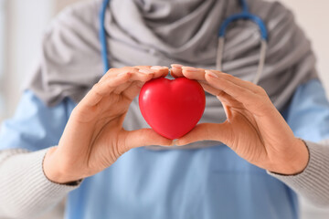 Wall Mural - Female Muslim doctor in hijab with heart at hospital, closeup