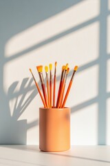 Poster - Minimalist Art Supplies Arrangement Sunlit Paintbrushes in Ceramic Holder for Creative Classroom Inspiration and Modern Design Aesthetics