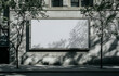© Gustav - Urban Billboard Mockup with Tree Shadows, An Ideal Template for Advertising and Promotional Campaigns in a City Environment on a Sunny Day