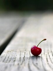 Poster - Single ripe cherry resting on a weathered wooden table showcasing its vibrant color and shine : Generative AI