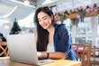 © Thinapob - Asian freelance people business female talking making using casual working with laptop computer and coffee at home in the living room indoors artificial rose bouquet of red and pink roses rose vase
