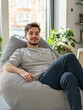 © Johannes - Young man relaxing comfortably in a grey sitting sack in a bright studio flat