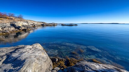 Poster - Beautiful serene rocky shoreline with clear blue water and calm reflections on a sunny day in nature : Generative AI
