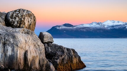 Fototapete - Serene Coastal Sunset Over Rocks with Snowy Mountains Creating Tranquil Landscape : Generative AI