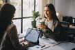 © ARMMY PICCA - Two young Asian business woman talk, consult, discuss working with new startup project idea presentation analyze plan marketing and investment in the office.